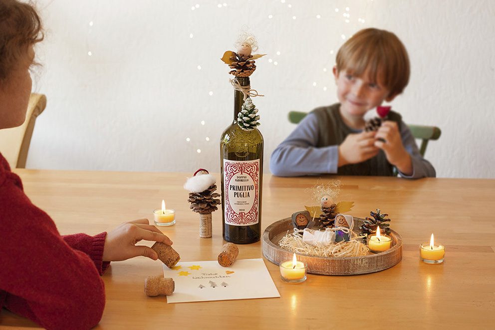 Zwei kleine Kinder sitzen sich an einem Tisch gegenüber und spielen und basteln mit Korken.