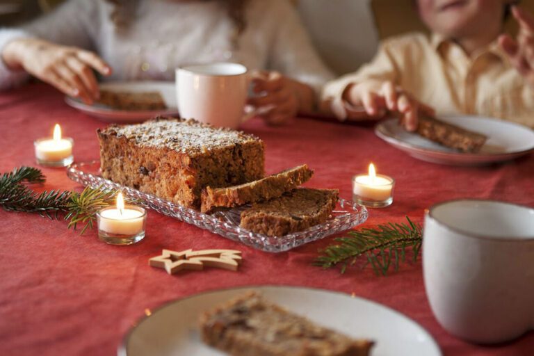 Das frische Früchtebrot steht auf einem gedeckten Tisch, der mit einer roten Tischdecke und Kerzen geschmückt ist.