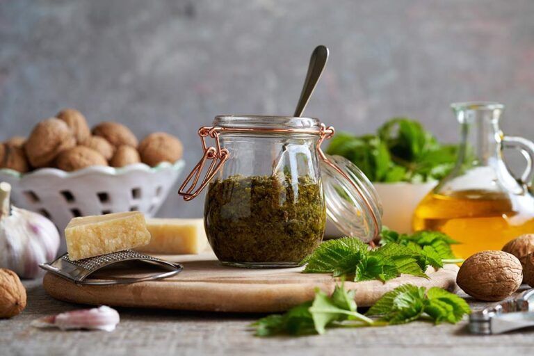 Giersch-Pesto steht mit den Zutaten für das Pesto auf einem Holzbrett.