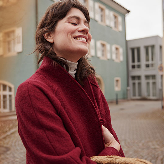 Frau in Bio-Baumwollkleidung vor einer Chocolaterie.