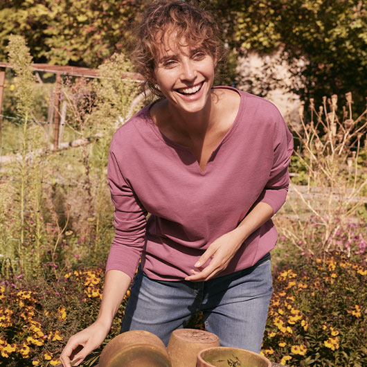Frau in einem Bio-Shirts fröhlich bei der Gartenarbeit