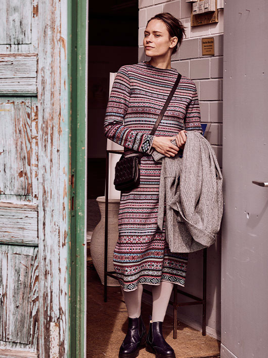 Frau in einem Strickkleid an einer Haustür