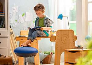 Junge liest auf seinem nachhaltigen höhenverstellbaren Kinder-Schreibtisch von Waschbär