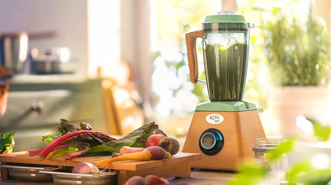 Standmixer mit verschiedenem Gemüse auf einer Arbeitsplatte