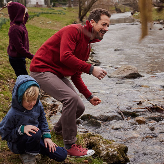 Mann im Bio-Troyer spielt mit Kindern am Wasser