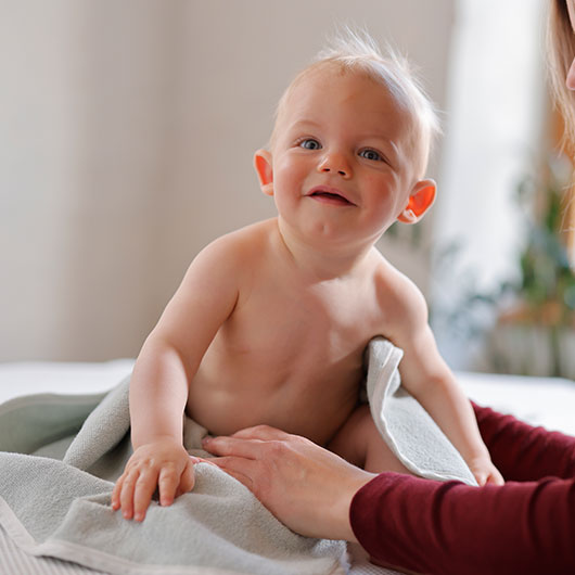 Baby in kuscheligem Bio-Handtuch, wird von seiner Mutter gehalten