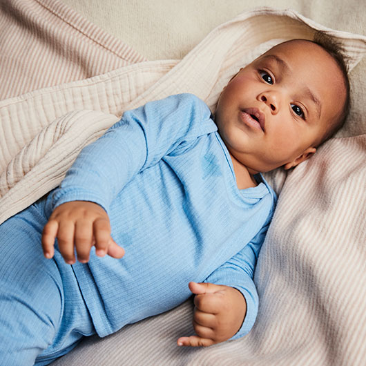 Baby in blauem Ajour-Langarmshirt aus Bio-Baumwolle