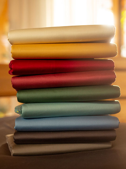 Stapel aus bunten Satin-Bettlaken in Bio-Qualität